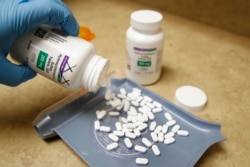 FILE - A pharmacy tech pours out pills of hydroxychloroquine, at Rock Canyon Pharmacy in Provo, Utah, May 20, 2020.
