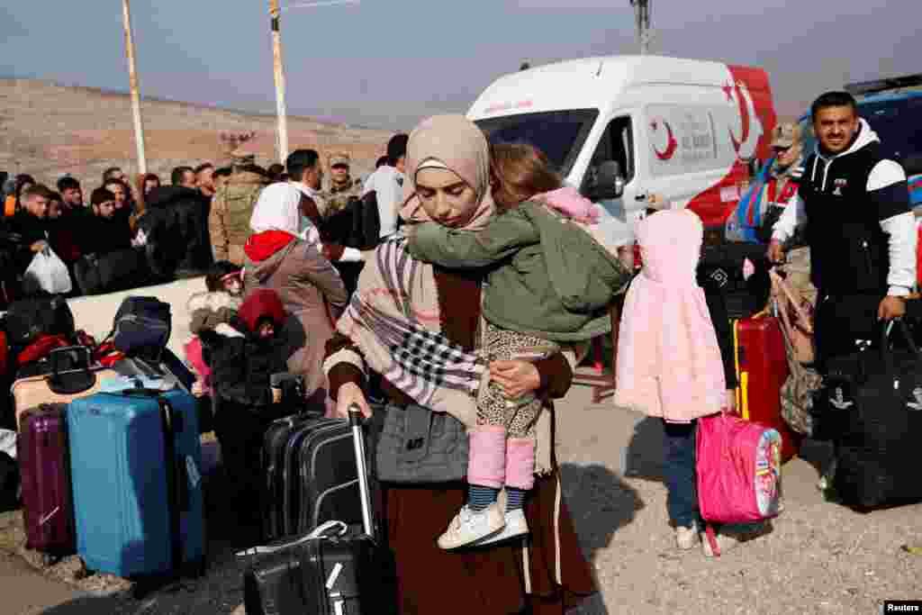 Syrian migrants wait at the Cilvegozu border gate to cross into Syria, after Syrian rebels announced that they have ousted President Bashar al-Assad, in the Turkish town of Reyhanli in Hatay province.