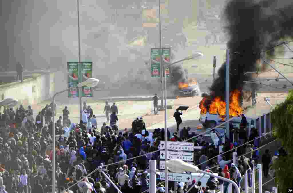 Mobil terbakar di samping pemakaman el Jallez di mana ribuan Tunisia yang berkumpul untuk menghadiri pemakaman pemimpin oposisi yang dibunuh, Shokri Belaid, dekat Tunis.