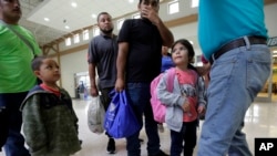 FILE - A group of immigrants from Honduras and Guatemala seeking asylum receive help the bus station after they were processed and released by U.S. Customs and Border Protection, June 21, 2018, in McAllen, Texas. 