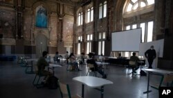 Students and their teacher wear face masks as they are spaced at a social distance from each other at the Royal Atheneum school, during the partial lifting of coronavirus, COVID-19, lockdown regulations in Antwerp, Belgium, May 18, 2020.