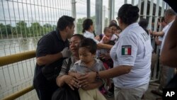 Seorang ibu migran Honduras dan putranya berjalan melalui jembatan setelah melintasi perbatasan antara Guatemala dan Meksiko, di Ciudad Hidalgo, Meksiko, 20 Oktober 2018. (Foto: dok).
