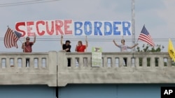 ARSIP – Para pengunjuk rasa dengan poster di Indianapolis, Indiana, melakukan unjuk rasa terhadap mereka yang beremigrasi secara ilegal, 18 Juli 2014 (foto: AP Photo/Darron Cummings, Arsip)