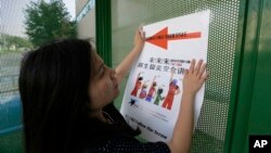 FILE - Ailu Xu, a graduate student from China, posts a sign directing Chinese students to new student orientation at the University of Texas at Dallas in Richardson, Texas, Aug. 22, 2015.