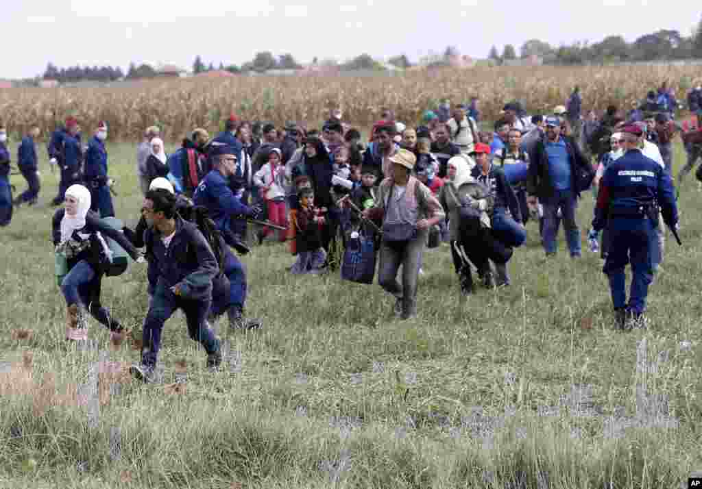 Migrants run away from a temporary holding center for asylum seekers in Roszke, southern Hungary, Sept. 8, 2015. Hungarian police struggled to control thousands of migrants hopping cross-border trains into Austria, taking advantage of country's surprise decision to stop screening international train travelers for travel visas, a get-tough measure that the country had launched only days before to block their path to asylum in Western Europe.