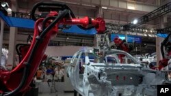 Para pengunjung memperhatikan robot perakit kendaraan dalam pameran World Robot Conference di Beijing, Kamis, 17 Agustus 2023. (Foto: Andy Wong/AP Photo).
