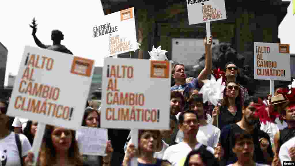 People hold posters during a Climate Change march to demand politicians take tougher action to protect the climate at Angel de la Independencia monument in Mexico City, Sept. 21, 2014.