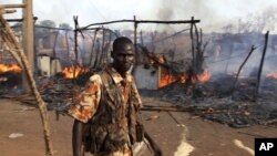 A policeman walks past the smouldering remains of a market in Rubkona near Bentiu in South Sudan, April 23, 2012.