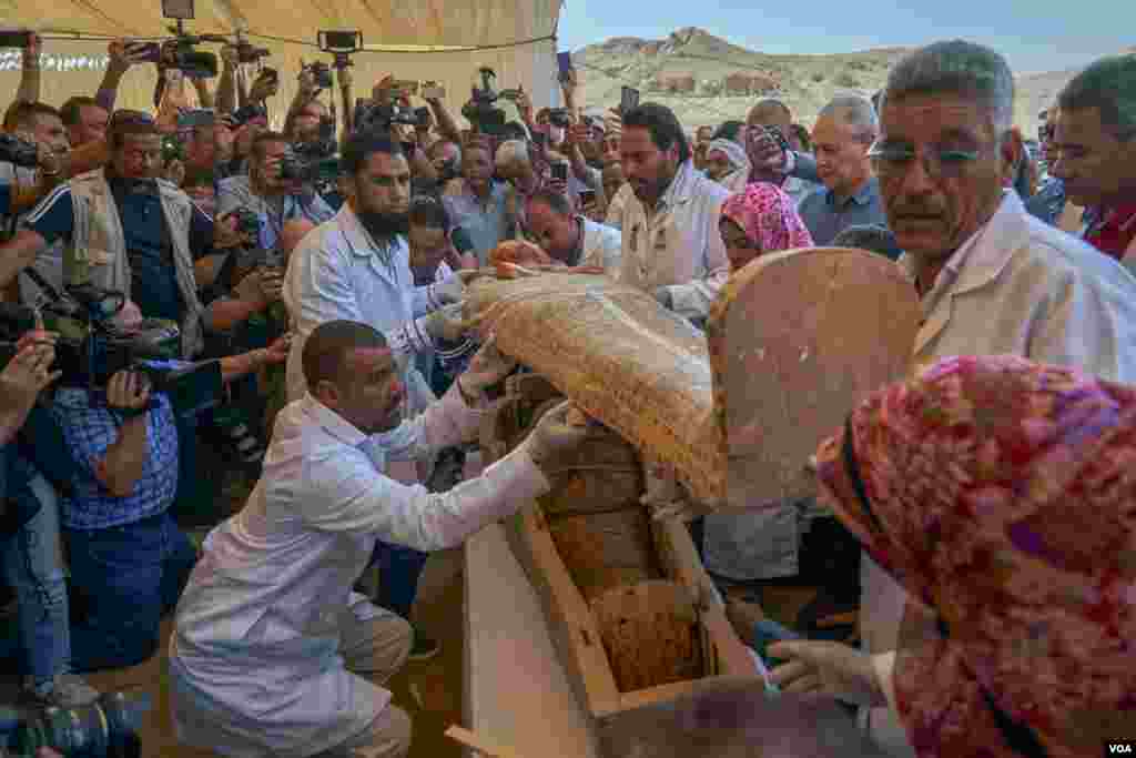 Restorers remove the coffin's cover to reveal the female mummy wrapped in linen and talismans to guide her in the afterlife. (H. Elrasam/VOA)