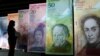 Seorang perempuan melihat versi besar mata uang Venezuela baru, yang disebut 'Strong Bolivar' di Caracas pada 2013, sebagai ilustrasi. (Foto: AP)