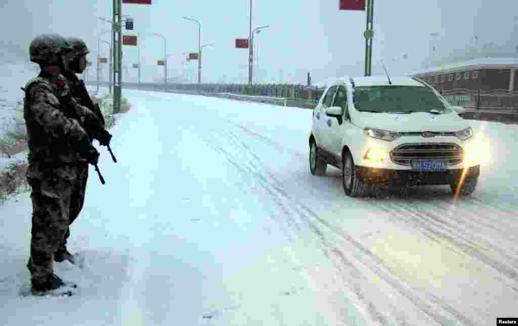 2017年12月27日,中国新疆维吾尔自治区阿勒泰市,军人在大雪中站岗,确保交通安全。