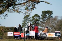 FILE - Poll workers assist voters on a brisk fall morning at the Efland Ruritan Club polling site in Efland, N.C., Nov. 3, 2020.