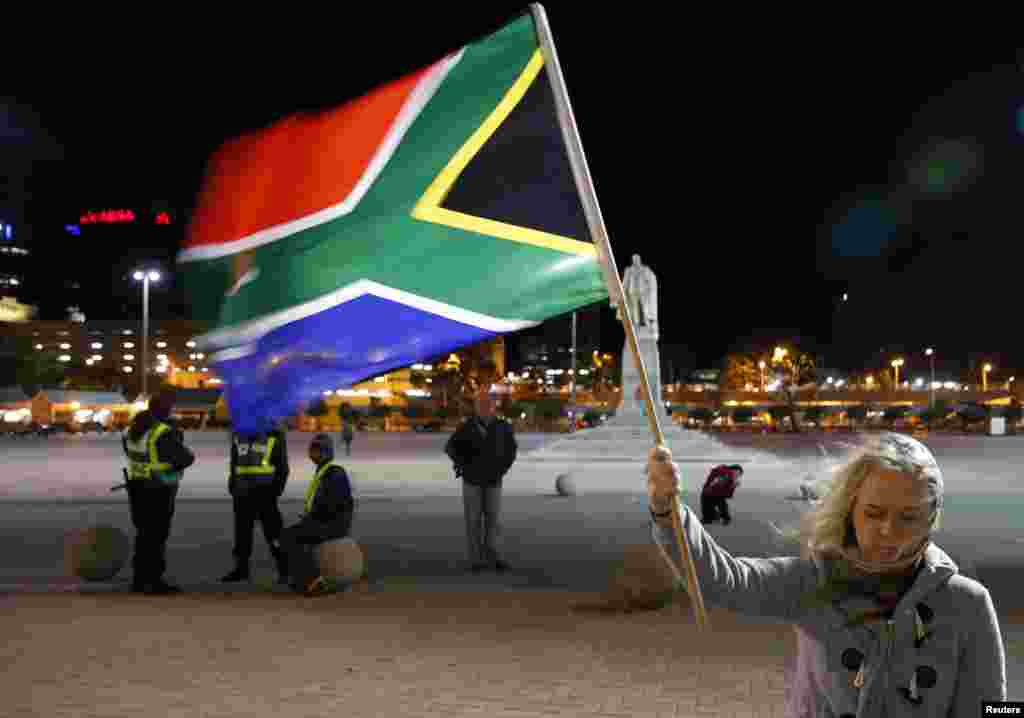 A girl holds a South African national flag as people mourn the death of Nelson Mandela outside Cape Town City Hall, Dec. 6, 2013.
