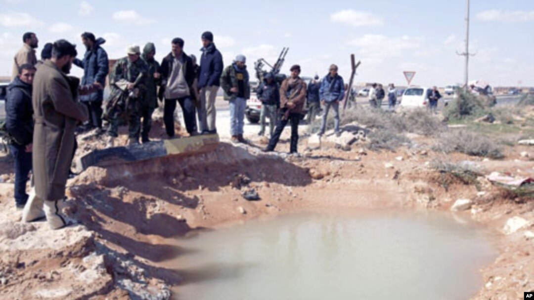 Anti-Gadhafi rebels survey the damage after an airstrike near the eastern city of Ras Lanuf, March 8, 2011