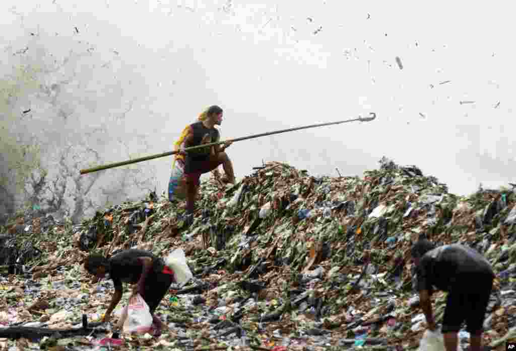 Seorang pria berdiri di atas tumpukan sampah yang terbawa ombak besar di Roxas Boulevard, Manila, mencari bahan-bahan yang bisa didaur ulang (1/8).