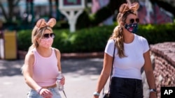 Para pengunjung Walt Disney World di Lake Buena Vista, Florida, mengenakan masker di tengah pandemi virus corona, 13 Agustus 2020. (Foto: Charles Sykes/Invision/AP) 