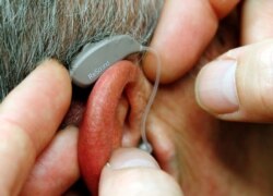 FILE - An employee of GN, the world's fourth largest maker of hearing aids, demonstrates the use of ReSound LiNX in Vienna, Nov. 22, 2013.