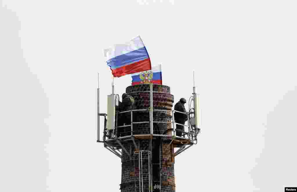 Pria-pria bersenjata yang diyakini sebagai tentara Rusia berjaga-jaga di menara dekat markas angkatan laut yang berbendera Rusia, di Sevastopol, Krimea (19/3).