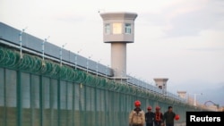 幾名工人在新疆一再教育營外走過。
