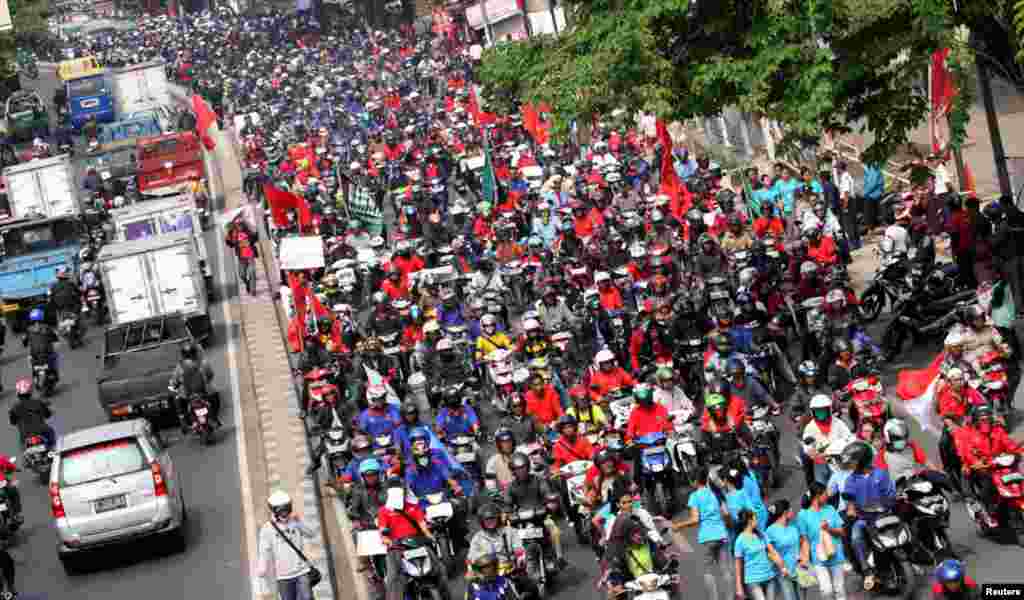 Para pekerja mengendarai motor sepanjang jalan selama demonstrasi di daerah industri di Tangerang.