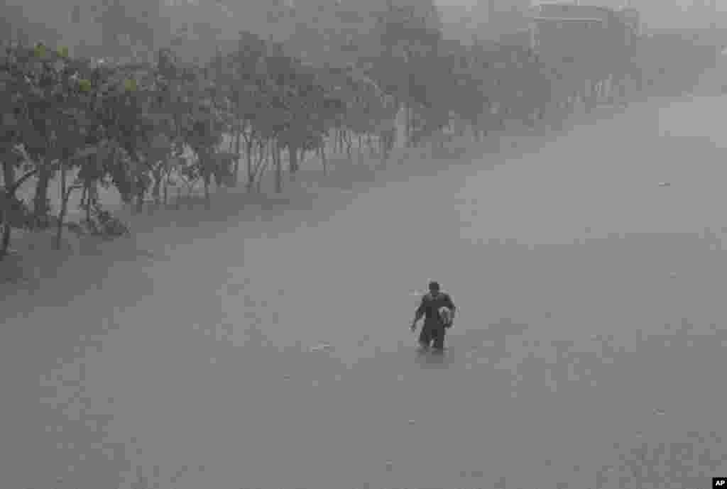 A man crosses a flooded highway in the financial district of Makati, south of Manila, Philippines, August 20, 2013.