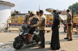 Policemen check a scooter at a security barricade on the road leading to a disputed religious site where Hindu religious groups are demanding the construction of a temple in Ayodhya, India, Oct. 22, 2019.