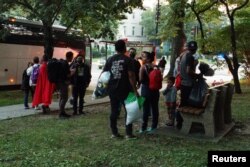 Sekelompok migran Venezuela, yang dikirim dengan bus dari tahanan di Texas dan kemudian diturunkan di luar Observatorium Angkatan Laut, kediaman resmi Wakil Presiden AS Kamala Harris, menunggu transportasi di Washington, AS, 17 September 2022. (Foto: Foto: REUTERS/Marat Sadana)
