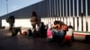 Arhiva - Migrant sedi sa svijom decom dok čekaju da čuju da li je njihov broj prozvan za apliciranje za azilu u SAD, na granici SAD i Meksika, u Tihuani, Meksiko, 25. januara 2019.