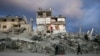 Yon moun pouse yon kabwet devan yon kay ki pasyelman kanpe ak dra ki sevi kom miray nan yon zon lame Izrayelyen preske ratibwaze net pandan ofansiv li nan Gaza siti, 5 Fevriye, 2025. 