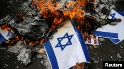 Seorang pengunjuk rasa membakar bendera Israel dalam unjuk rasa memprotes keputusan Washingtong untuk mengakui Yerusalem sebagai Ibu Kota Israel, di luar Kedutaan Besar Amerika Serikat di Jakarta, 15 Desember 2017.
