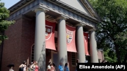 People are led on a tour on the campus of Harvard University in Cambridge, Mass