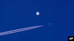 Sebuah jet tempur terbang di dekat balon besar yang melayang di atas Samudra Atlantik, tepat di lepas pantai Carolina Selatan dekat Pantai Myrtle, Sabtu, 4 Februari 2023. (Chad Fish via AP)