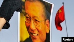 一位抗議者在中國駐奧斯陸大使館門外舉著劉曉波的照片。（資料圖片）