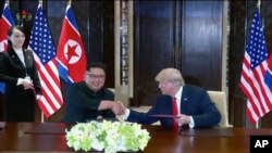 Pemimpin Korea Utara Kim Jong Un bersalaman dengan Presiden Donald Trump disaksikan oleh adik Kim Jong Un, Kim Yo Jong, dalam KTT di Singapura, 12 Juni 2018.