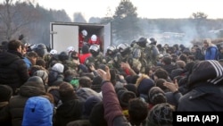 Prajurit Belarusia mengendalikan situasi sementara para migran antre untuk mendapatkan bantuan kemanusiaan di perbatasan Belarusia-Polandia dekat Grodno, Belarus, Jumat, 12 November 2021. (Ramil Nasibulin/BelTA pool photo via AP)