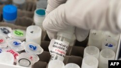 Seorang peneliti mengangkat botol vaksin Covid-19 di laboratorium Novavax di Gaithersburg, Maryland, salah satu laboratorium yang mengembangkan vaksin untuk virus corona. (Foto: AFP)
