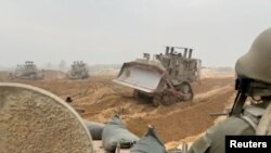 以色列軍方2023年10月29日公佈的加沙走廊地面行動的影片截圖顯示以軍裝甲車在某處地點等待裝甲車推土機清路。