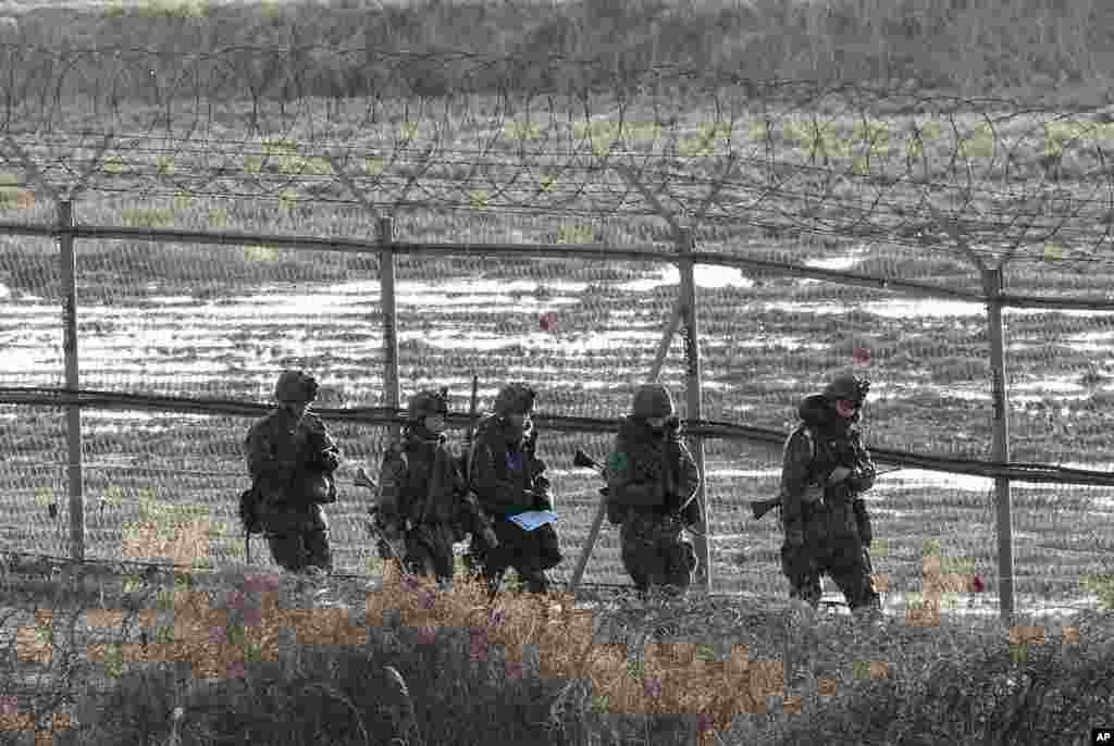 South Korean Army soldiers patrol along a barbed-wire fence near the border village of Panmunjom in Paju, South Korea, March 11, 2013.
