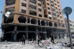 People inspect the rubble of a damaged building which was hit by an Israeli airstrike, in Gaza City, May 12, 2021.