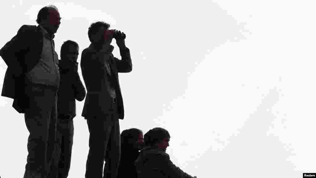 Turkish Kurds watch over the Syrian town of Kobani as they stand on top of a hill near Mursitpinar border crossing in the southeastern Turkish town of Suruc in Sanliurfa province, Oct. 14, 2014.