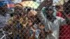 FILE - People stand behind a gate at Mpoko Airport in Bangui, Central African Republic, as food is being unloaded from a cargo aircraft.