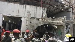 Police and rescuers stand in front of the bombed office of ThisDay, an influential daily newspaper in Abuja, Nigeria, April. 26, 2012.