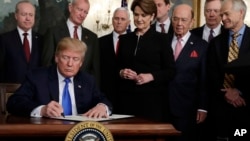 President Donald Trump signs a presidential memorandum imposing tariffs and investment restrictions on China in the Diplomatic Reception Room of the White House, March 22, 2018.