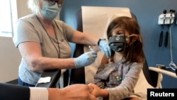 FILE - Bridgette Melo, 5, holds the hand of her father, Jim Melo, during her inoculation of one of two reduced 10 ug doses of the Pfizer BioNtech COVID-19 vaccine during a trial at Duke University in Durham, North Carolina, September 28, 2021, in a still 