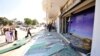People stand in front of a damaged Marks & Spencer store after a blast in Benghazi, Libya, Aug. 8, 2013.