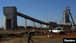 FILE - A man walks past the Doornkop Gold Mine, about 19 miles west of Johannesburg.