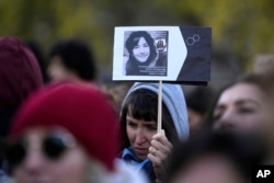 Seorang perempuan menunjukkan foto Giulia Cecchettin yang diduga dibunuh oleh mantan pacarnya, dalam demo memperingati Hari Internasional Penghapusan Kekerasan Terhadap Perempuan, di Milan, Italia, Sabtu, 25 November 2023. (Foto: Luca Bruno/AP Photo)