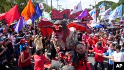 Aktivis menghancurkan patung Presiden Filipina Rodrigo Duterte, tengah, bersama putrinya walikota Davao, Sara, kanan, dan Ferdinand 'Bongbong' Marcos Jr., putra mendiang diktator. (Foto: AP)