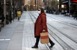 Seorang wanita melintasi jalan yang biasanya sibuk di Sydney, Rabu, 7 Juli 2021. (AP)