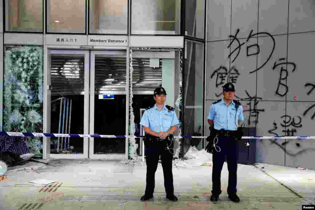 香港警察2019年7月2日站在立法會外,可以看到外牆上被抗議者在前一晚示威時塗寫的塗鴉。
